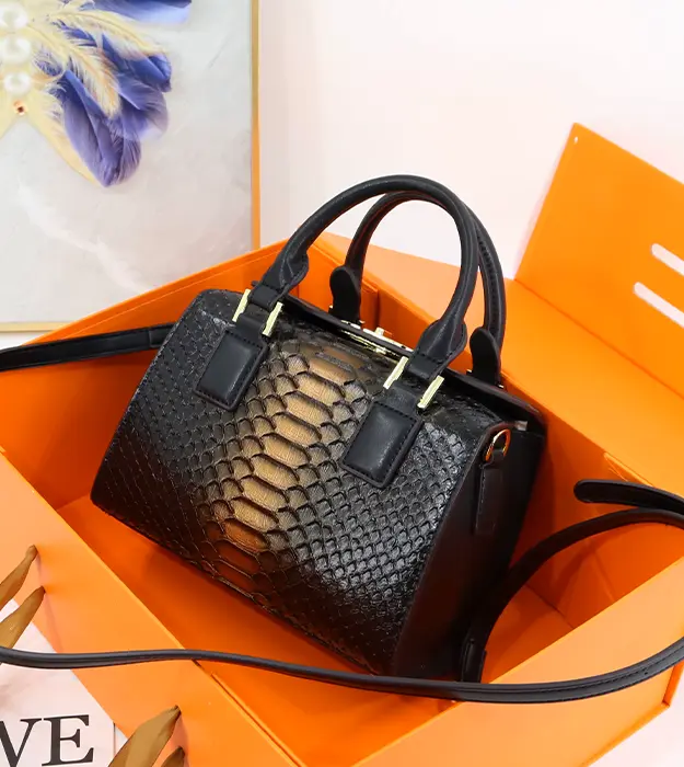 Crno-zlatna luksuzna ženska torba Luméa Éclipse sa zmijskim dezenom, postavljena na beloj pozadini